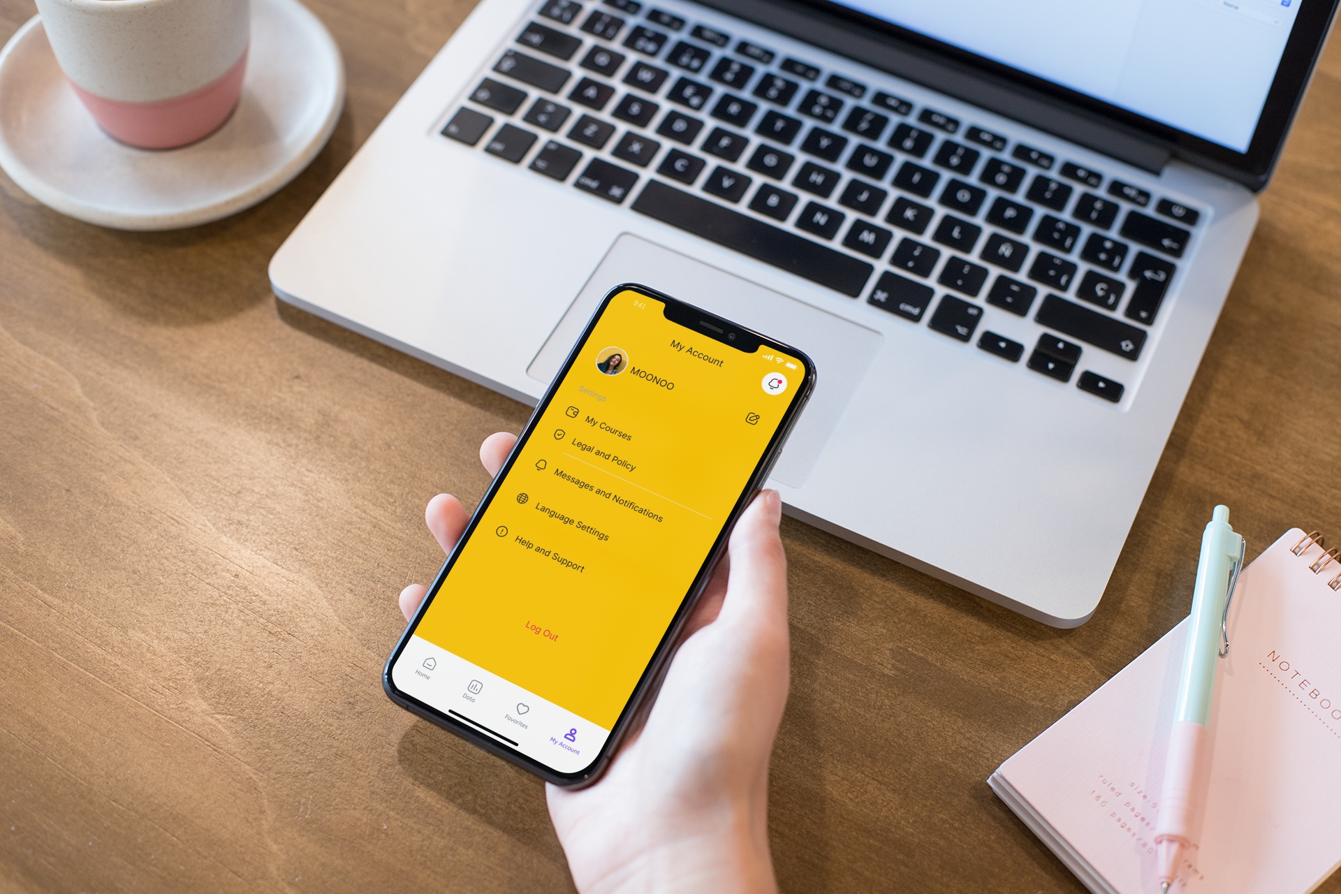 mockup-of-a-girl-s-hand-holding-an-iphone-xs-max-over-a-wooden-desk-25357.jpg